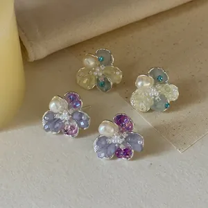 Detailed view of ice-transparent crystal and pearl flower stud earrings in French style
