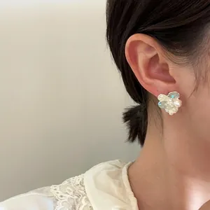 Close-up view of elegant crystal and pearl flower stud earring worn by a model