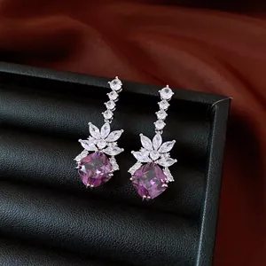 Close-up of vintage style silver drop earrings with purple cubic zirconia stones.