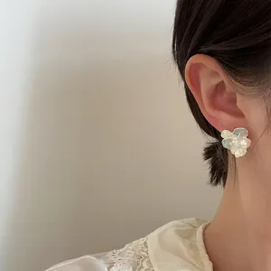 Detailed view of elegant ice-transparent crystal and pearl flower stud earring worn on ear