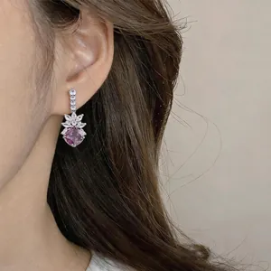 Close-up detail of vintage purple zircon and silver needle earrings worn on ear.