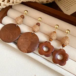 Close-up of ethnic raffia and wooden drop earrings with circular and flower designs.