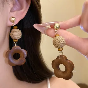 Detail view of ethnic retro earrings featuring raffia balls and wooden flower pendants