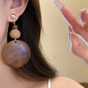 Detail of retro ethnic raffia and wood circular drop earrings on model