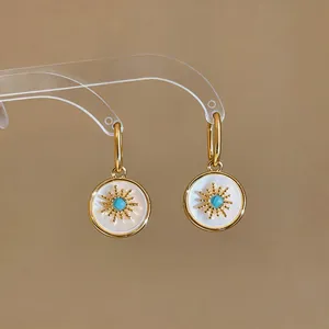 Close-up of vintage 24k gold plated earrings with sunburst mother of pearl drop