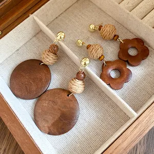 Detail view of ethnic retro style raffia and wooden drop earrings inside a jewelry box