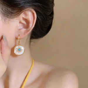 Close-up detail of 24k gold-plated sunburst earrings with mother-of-pearl inlay