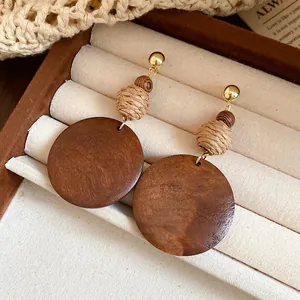 Detailed view of handmade ethnic earrings featuring woven raffia and circular wood discs
