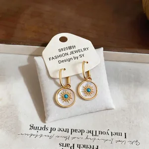Detailed view of vintage gold-plated hoop earrings with mother-of-pearl flower inlay.