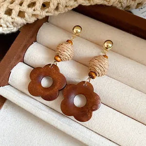 Detail view of ethnic wooden flower drop earrings with raffia beads in a jewelry box