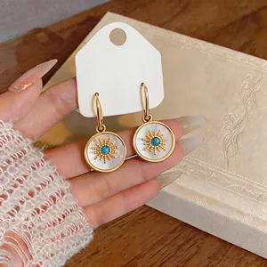 Close-up of elegant 24k gold-plated sunburst earrings with white mother-of-pearl inlay