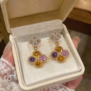 Elegante Blumenstecker mit bunten Zirkonsteinen, präsentiert in einer weißen Schmuckschachtel