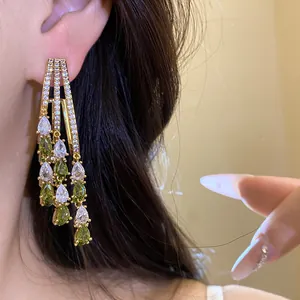 Detailed view of elegant 18k gold plated tassel earrings featuring green and white zircons