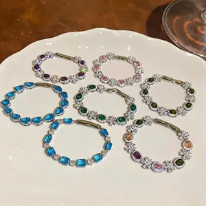 Collection of elegant colorful zircon flower bracelets displayed on a white decorative plate.