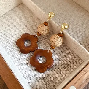 Macro view of handmade retro earrings featuring raffia beads and wooden flower pendants