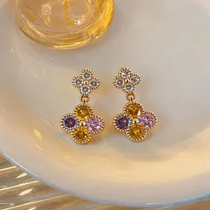 Detailansicht goldener Blumenohrringe mit bunten, funkelnden Zirkoniasteinen.