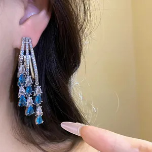 Close-up of elegant silver needle tassel earrings with blue and white water-drop zircons