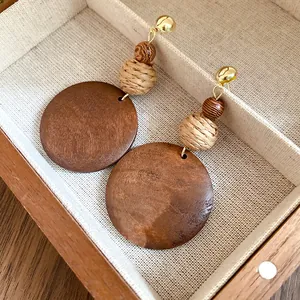 Detail view of vintage ethnic earrings with circular wood pendants and woven raffia beads