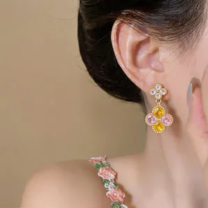Detailansicht eleganter Blumenohrringe mit gelben und rosa Zirkonia-Steinen.