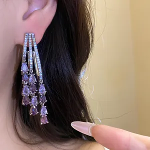 Macro detail of 18k gold plated silver needle earrings with purple zircon tassels.