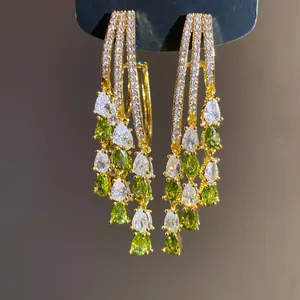 Detailed macro view of 18k gold plated tassel earrings with green and white teardrop cubic zirconia