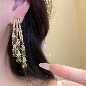 Detailed view of gold-plated tassel earrings with green and white teardrop zircons.