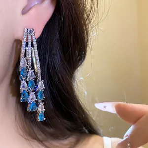 Close-up detail of luxury blue and white teardrop zircon tassel earrings worn on ear