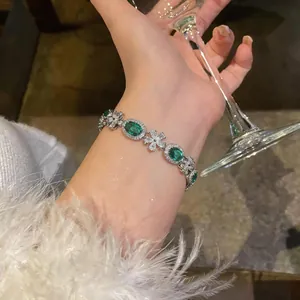 Close-up detail of an elegant silver-toned bracelet with green oval zircons worn on a wrist