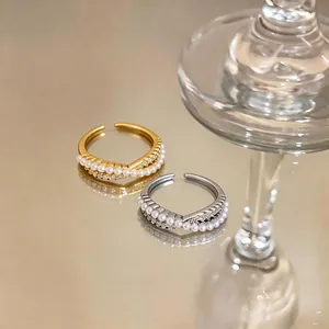 Elegant crossover rings with pearls and sparkling zircons in gold and silver tones.