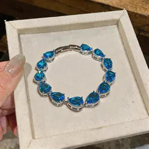 Close-up of blue water-drop zircon bracelet in a minimalist beige gift display box