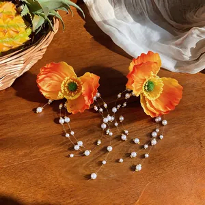 Detailed view of orange fabric flower earrings with long pearl tassels design