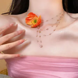 Close-up detail of a sweet orange fabric poppy necklace with delicate beads on a model.