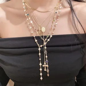 Close-up of elegant layered gold necklace with cross pendant and pearl beads
