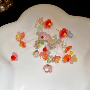 Detailed view of colorful resin flower tassel earrings displayed on a white ceramic dish