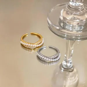 Detailed view of elegant gold and silver crossover rings with pearls and zircons