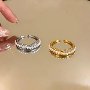 Detail of gold and silver zircon crossover rings with delicate pearls on a mirror