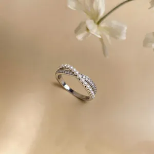 Elegant crossover ring featuring delicate pearls and pavé cubic zirconia accents.