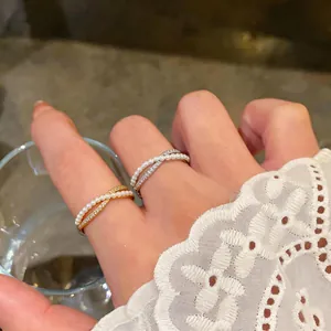 Close-up of elegant pearl and zircon crossover rings worn with a white lace sleeve cuff
