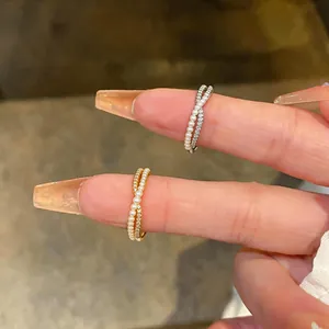 Detailed view of the gold and silver intertwined rings with small pearls and zircons.