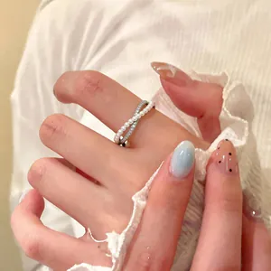 Elegant close-up of a criss-cross silver ring with white pearls and sparkling zircons