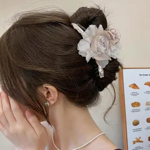 Vista laterale di un'elegante pinza per capelli a fiore in tessuto champagne in uno chignon