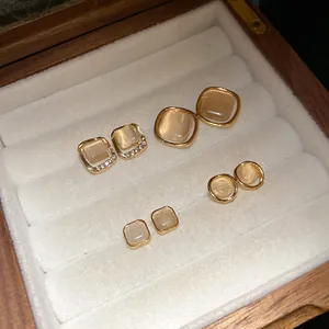 Set of four pairs of vintage cat's eye stone stud earrings in a wooden jewelry box display.