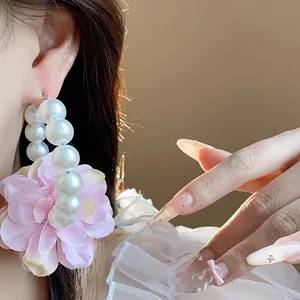 Dettaglio di orecchini a cerchio stile francese con fiori in tessuto rosa e perle bianche