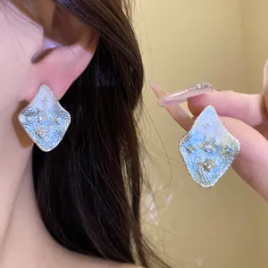 Detailed view of niche design silver pleated rhombus stud earrings featuring inlaid zircon stones