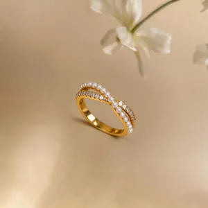 Detailed view of an elegant gold crisscross ring featuring pearls and sparkling zircons
