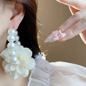 Primo piano dettagliato di orecchini a cerchio con perle e un fiore in tessuto bianco