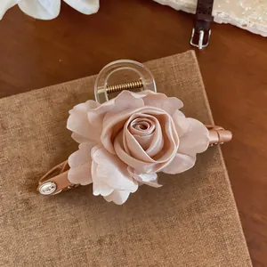 Dettaglio di un elegante fermaglio per capelli con rosa in tessuto e cuoio beige
