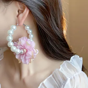 Dettaglio di orecchini a cerchio in stile francese con fiore in tessuto rosa e perle
