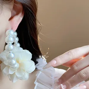 Primo piano dettagliato di eleganti orecchini a cerchio con fiori in tessuto e perle