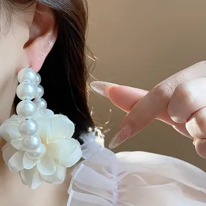 Primo piano squisito di un elegante orecchino a cerchio con fiori in tessuto e perle